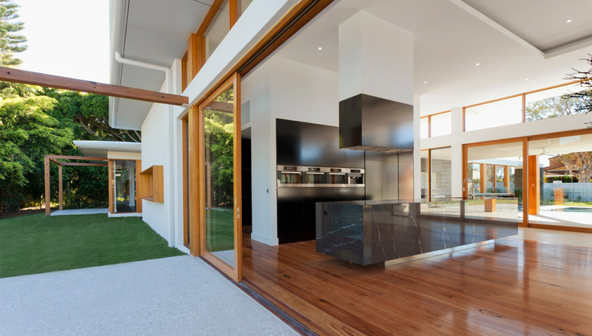A large modern luxury kitchen with hardwood floors and black marble that recently underwent a luxury kitchen renovation.