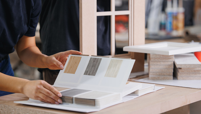 A Perth kitchen renovation specialist assessing multiple design options for a luxury kitchen renovation including colour swatches, handles and tiles.